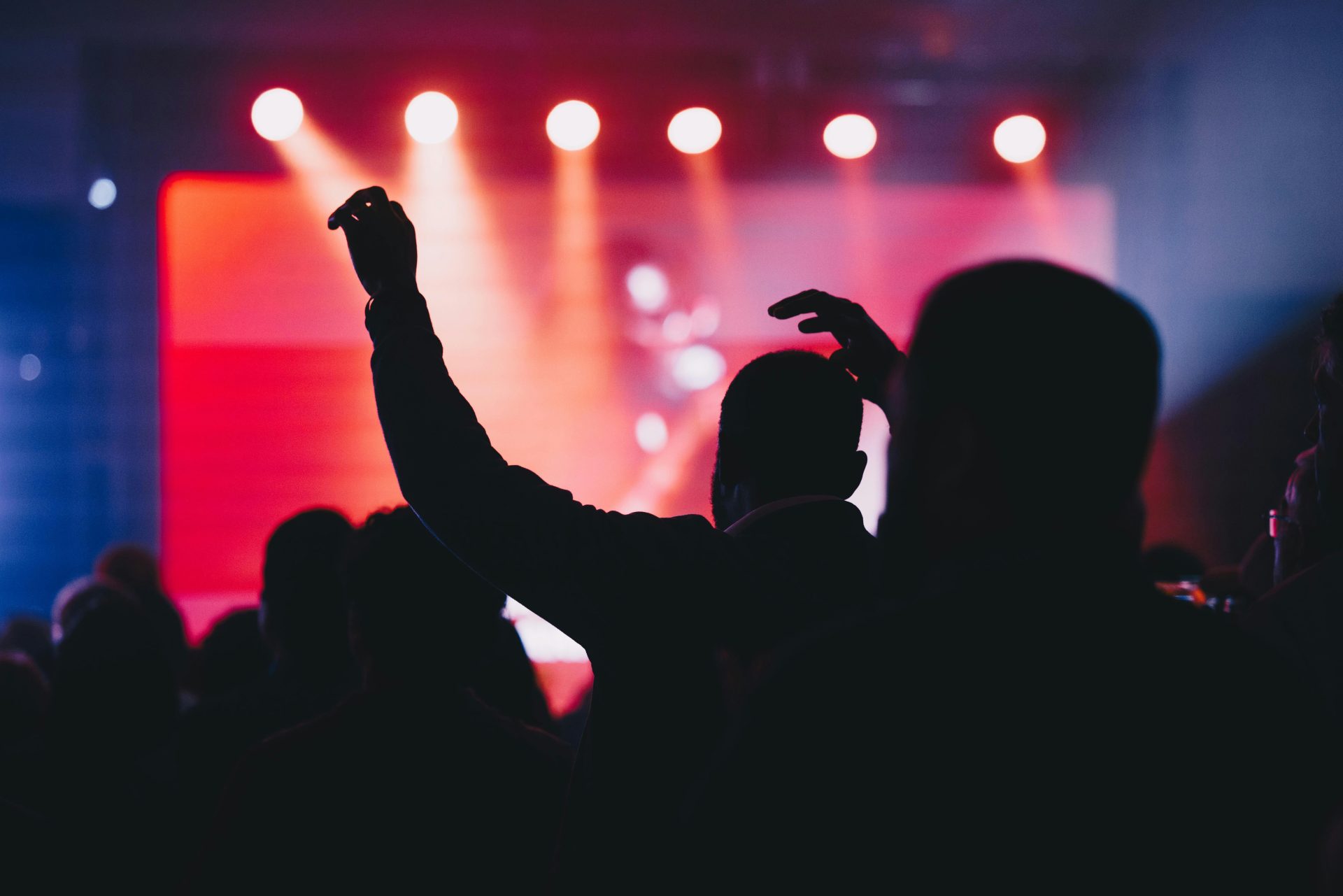 A crowd of people at a concert with their arms in the air